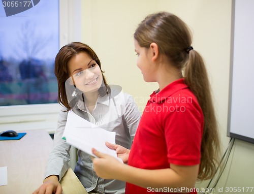 Image of school girl with notebook and teacher in classroom