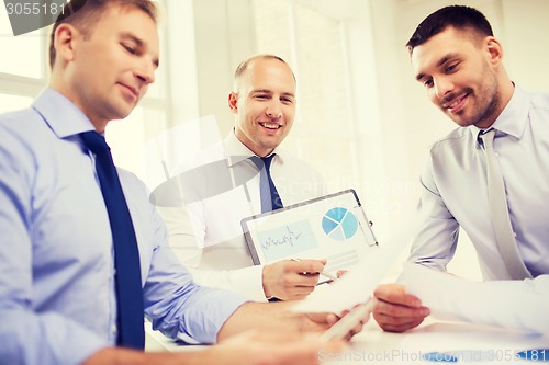 Image of smiling businessmen with papers in office