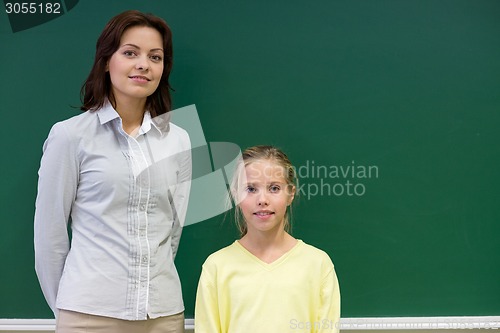 Image of little school girl with teacher at blackboard