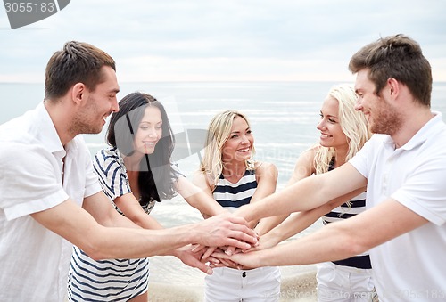 Image of smiling friends putting hands on top of each other