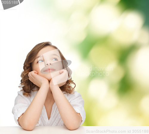 Image of beautiful girl sitting at table and looking up