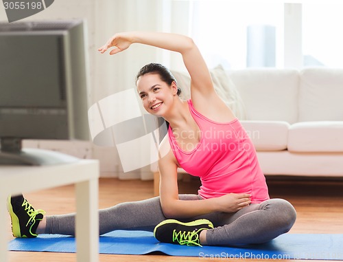 Image of smiling teenage girl streching on floor at home