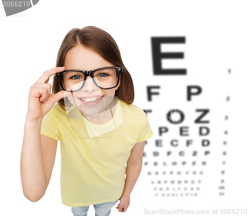 Image of smiling little girl in eyeglasses with eye chart