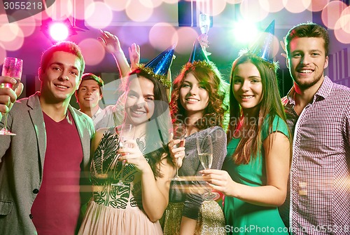 Image of smiling friends with glasses of champagne in club