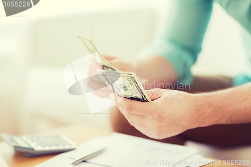 Image of close up of man counting money and making notes