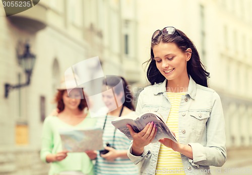 Image of smiling teenage girls with city guides and camera