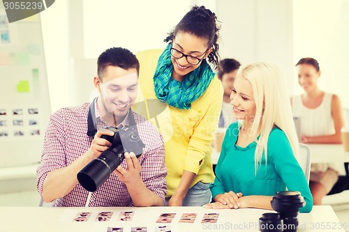 Image of smiling team with photocamera working in office