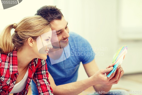 Image of smiling couple looking at color samples at home