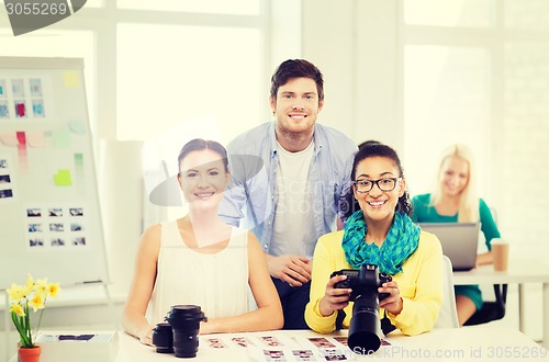 Image of smiling team with photocamera working in office