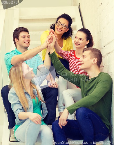 Image of smiling students making high five gesture sitting