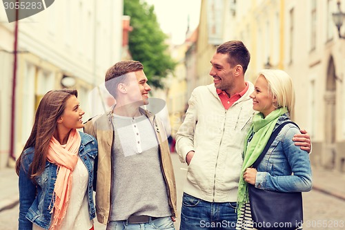 Image of group of smiling friends walking in the city