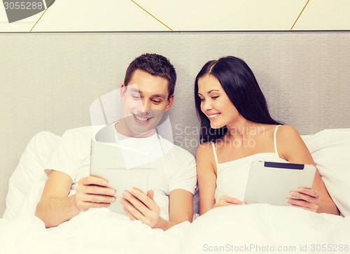 Image of smiling couple in bed with tablet pc computers