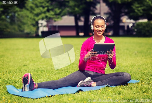 Image of smiling woman with tablet pc outdoors