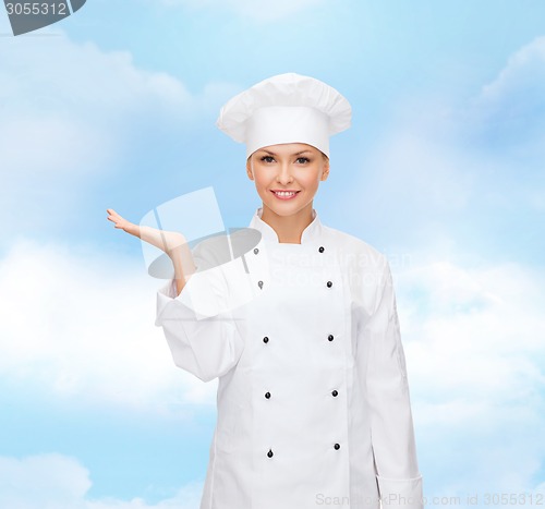 Image of smiling female chef holding something on hand