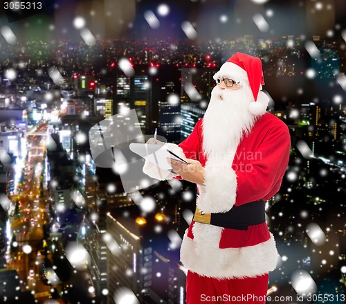 Image of man in costume of santa claus with notepad