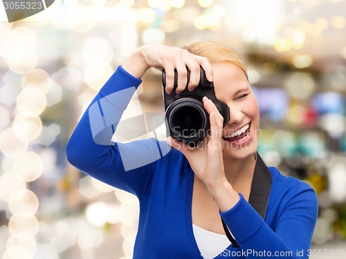 Image of smiling woman taking picture with digital camera