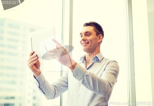 Image of smiling businessman with tablet pc in office