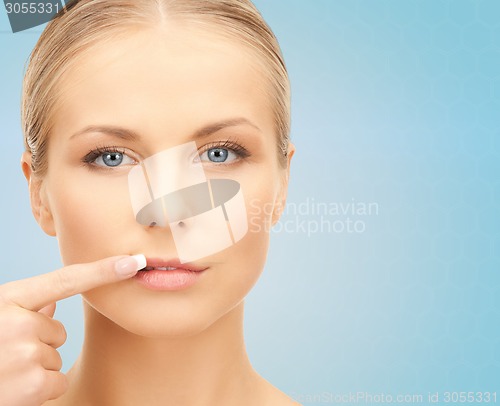 Image of beautiful young woman pointing finger to her lips