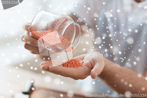Image of close up of man emptying jar with red lentils