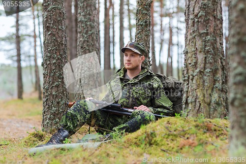 Image of young soldier or hunter with gun in forest