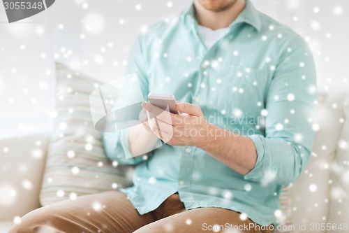 Image of close up of man sitting with smartphone at home