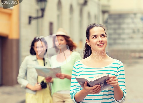 Image of smiling teenage girls with city guides and camera