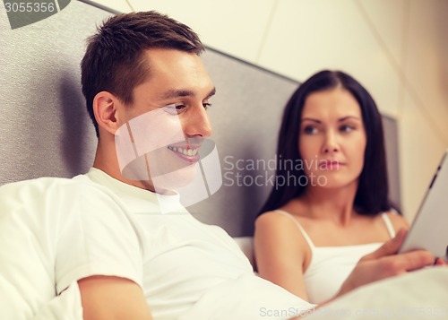 Image of smiling couple in bed with tablet pc computers