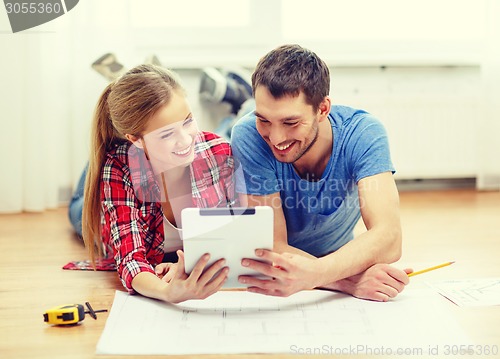 Image of smiling couple looking at tablet pc at home