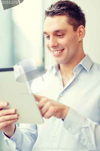 Image of smiling businessman with tablet pc in office