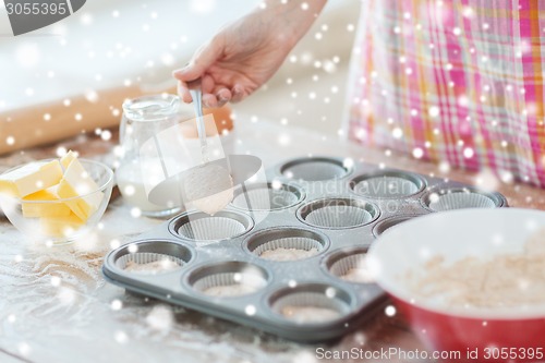 Image of close up of woman filling muffins molds with dough