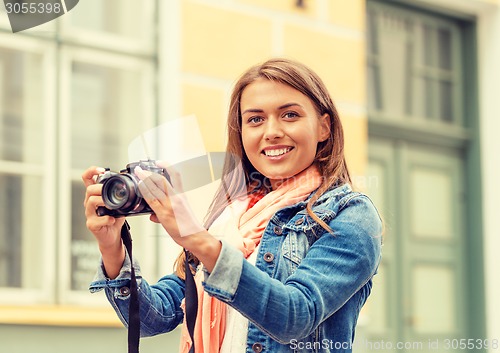 Image of smiling girl with digiral photocamera in the city