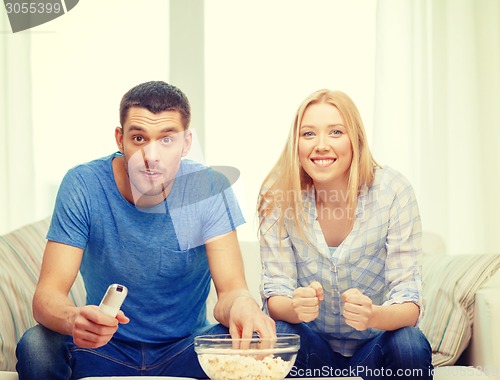 Image of smiling couple with popcorn cheering sports team