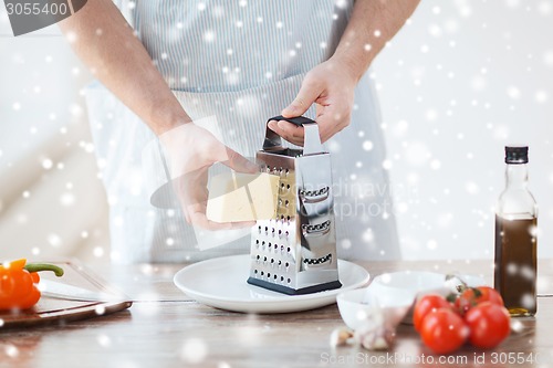 Image of close up of male hands with grater grating cheese