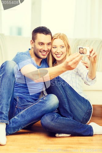 Image of smiling couple taking picture with digital camera