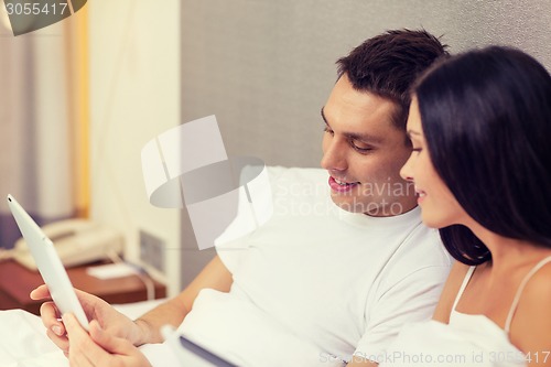 Image of smiling couple in bed with tablet pc computers