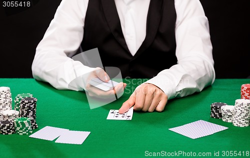 Image of holdem dealer with playing cards and casino chips