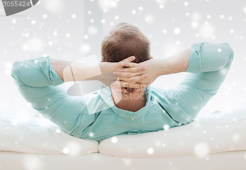 Image of man lying or sitting on sofa at home from back