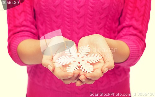 Image of close up of woman in sweater holding snowflake