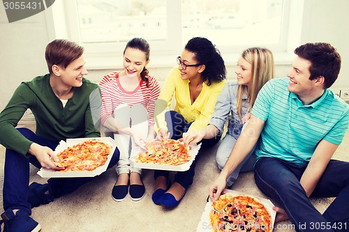 Image of five smiling teenagers eating pizza at home