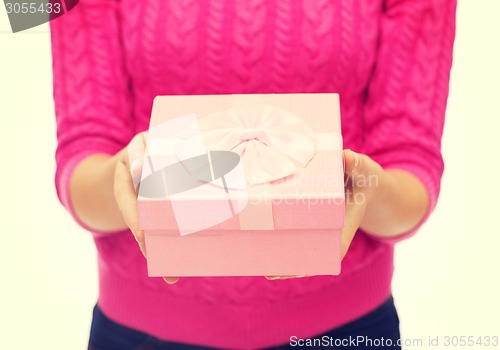 Image of close up of woman in pink sweater holding gift box