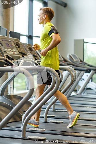 Image of man with smartphone exercising on treadmill in gym