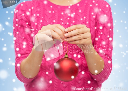 Image of close up of woman in sweater with christmas ball