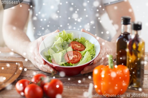 Image of close of male hands holding bowl with salad