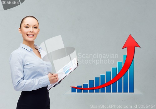 Image of young smiling businesswoman with clipboard and pen