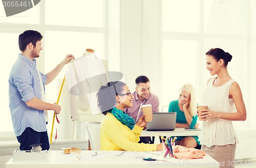 Image of smiling fashion designers working in office