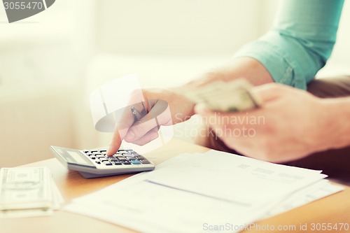 Image of close up of man counting money and making notes