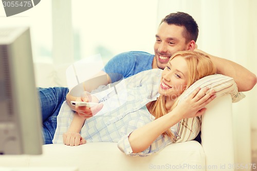 Image of smiling couple watching movie at home
