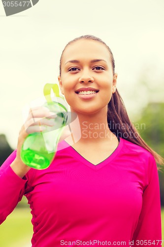 Image of smiling woman drinking from bottle