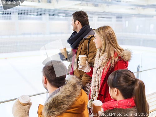 Image of happy friends with coffee cups on skating rink