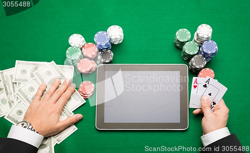 Image of casino poker player with cards, tablet and chips